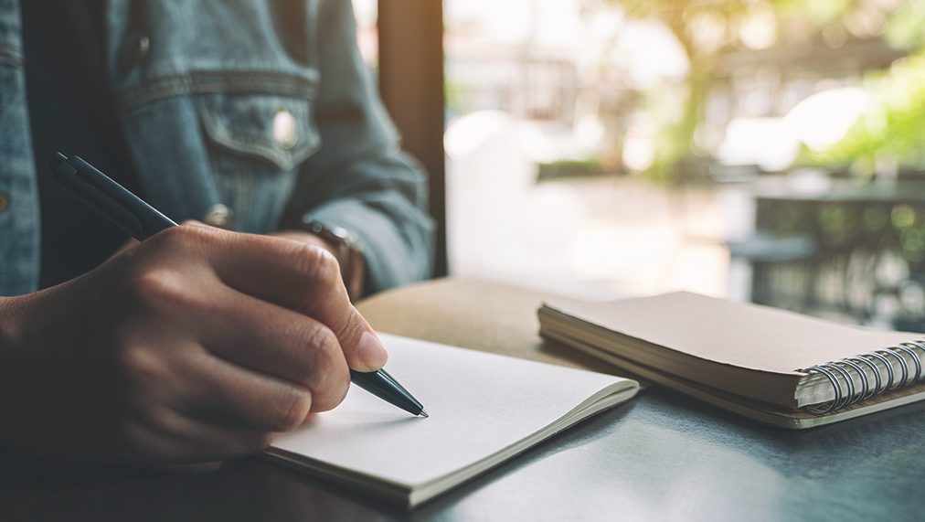 Person writing on a blank page