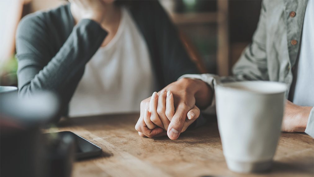 Two persons holding hands in sympathy